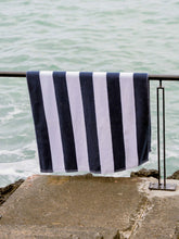 Load image into Gallery viewer, Navy and white striped towel hanging on a railing by the water.