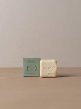 Load image into Gallery viewer, Bar of soap and its packaging on a beige surface with a neutral background