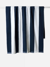 Load image into Gallery viewer, Navy and white striped towel hanging on a rack against a white background