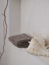 Load image into Gallery viewer, Striped fabric and seashell on a white surface with a branch in the background