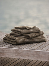 Load image into Gallery viewer, Stack of brown towels on a wooden surface with a blurred natural background