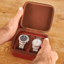 Load image into Gallery viewer, A person holding open a brown vegan leather watch case with two watches inside.